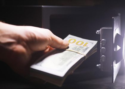 Hand placing a bundle of cash into an open home safe at night